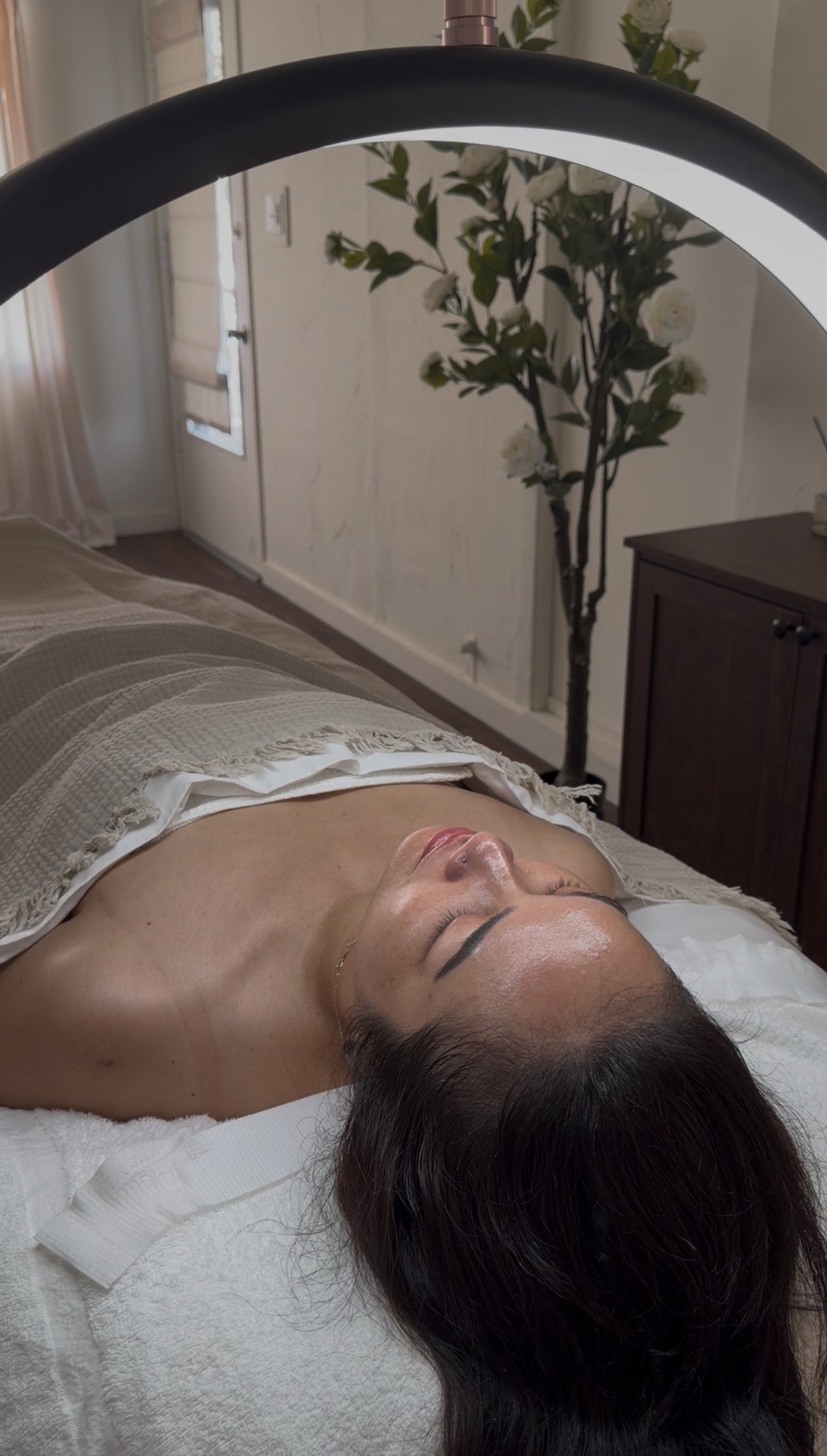 Client receiving a Korean-inspired facial in Long Beach with hydrated, glowing skin under LED light therapy in a calming spa setting.